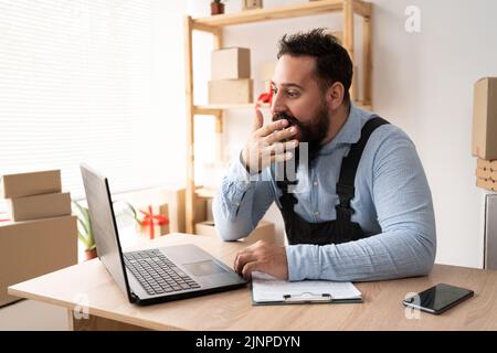 un jeune homme d'affaires fatigué bâille au travail, un homme d'affaires bât au bureau, une personne avec l'anxiété de santé, une mauvaise frustration Banque D'Images