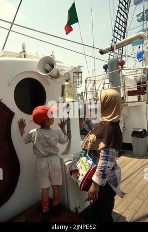 Une femme et un enfant prêtant attention à une cloche sur le KRI Dewaruci (Dewa Ruci), un grand navire indonésien, comme la goélette de type barquentine est ouverte aux visiteurs publics au port de Kolinlamil (port de la Marine) à Tanjung Priok, dans le nord de Jakarta, Jakarta, Indonésie. Banque D'Images