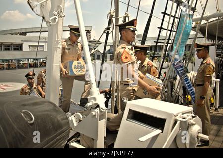 Des cadets de la Marine transportant de l'eau minérale dans des boîtes alors qu'ils sont sur le point d'entrer dans la chambre des cadets de KRI Dewaruci (Dewa Ruci), un grand navire indonésien, car la goélette de type barquentine est ouverte aux visiteurs publics au port de Kolinlamil (port de la Marine) à Tanjung Priok, dans le nord de Jakarta, en Indonésie. Banque D'Images