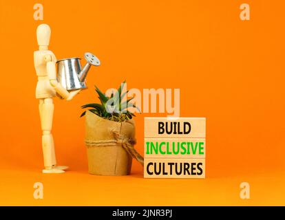 Construire le symbole des cultures inclusives. Les mots-concepts construisent des cultures inclusives sur des blocs de bois. Modèle homme d'affaires. Magnifique arrière-plan orange. Business bui Banque D'Images