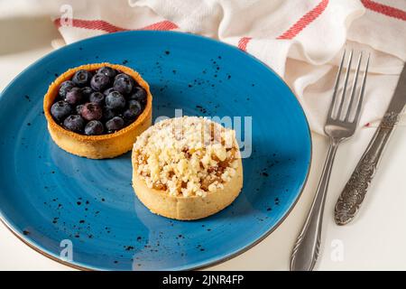 Tarte aux pommes et aux myrtilles fraîchement cuite sur une assiette en porcelaine bleue Banque D'Images