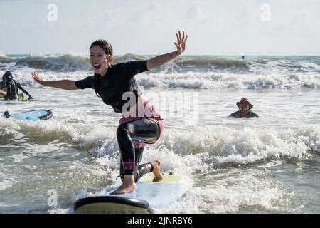 Un étudiant de surf conduit avec succès une vague à Khao Lak, le seul endroit connu pour le surf en Thaïlande. Pour développer le tourisme dans les régions mal desservies de Thaïlande, l'agence de marketing du pays, l'Autorité du tourisme de Thaïlande (TAT), a lancé des campagnes pour promouvoir le tourisme international dans le sud dans le cadre de sa campagne « nouveaux chapitres étonnants ». Cette partie spécifique de la campagne cible Phuket, Phangan, et Khao Lak, une région connue pour être le seul endroit pour aller surfer en Thaïlande. Banque D'Images