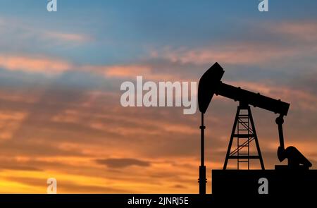 pompe à huile isolée sur fond de coucher de soleil flou. Banque D'Images