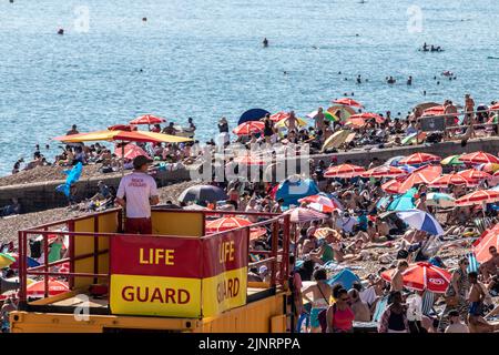 Brighton, Royaume-Uni. 13th août 2022. Ce samedi, des milliers de personnes ont afflué vers Brighton Beach, pour tirer le meilleur parti du temps chaud. Un aperçu des parasols rouges (sponsorisés par Walls Ice Cream ) peut être vu s'étendant de Brighton le long de Hove Credit: @Dmonuk/Alay Live News Banque D'Images