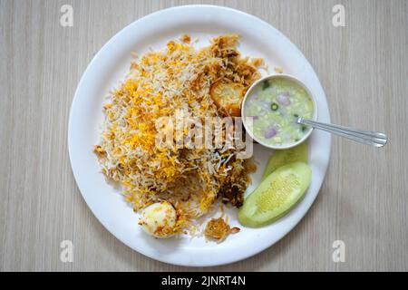 Vue sur le dessus de la table de l'assiette de Biryani de poulet indien servie avec des œufs et de la pomme de terre dans une assiette blanche Banque D'Images