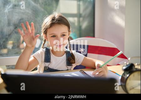 Formation à distance. La jeune fille de première année de race blanche est assise à la maison à un bureau avec des études numériques sur tablette à l'école en ligne Banque D'Images