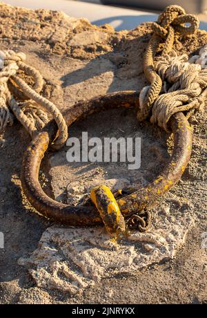 anneau de fer et vieux cordes sur un quai pour attacher et amarrer des navires et des bateaux le long du mur du port, amarrer anneau sur un quai vieux cordes. Banque D'Images