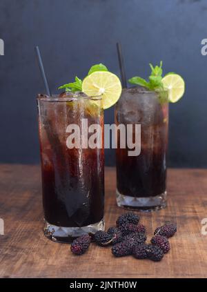 Deux cocktails au vin de mûrier sur table en bois et fond noir Banque D'Images