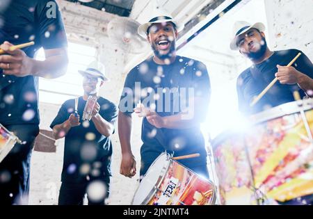 Bien fournir l'énergie. Portrait à angle bas d'un groupe de jeunes hommes de tambours de belle jouant au Carnaval. Banque D'Images