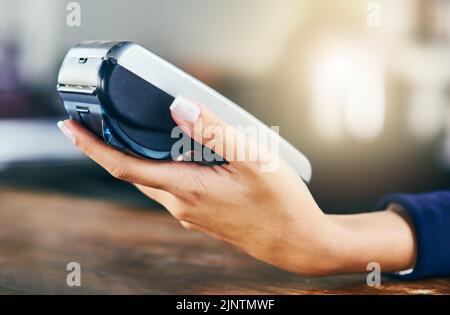 L'électronique est la voie à suivre pour payer. Gros plan d'une personne méconnaissable tenant une machine à cartes à l'intérieur d'un café pendant la journée. Banque D'Images