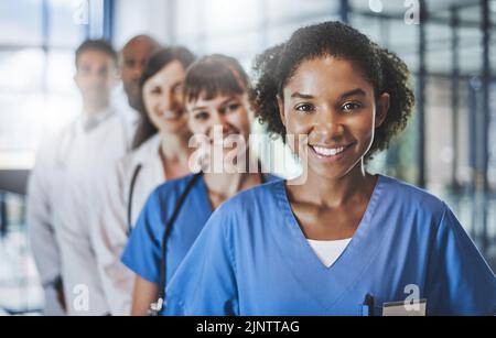 En ligne pour vous maintenir bien. Portrait d'une équipe diversifiée de médecins debout ensemble dans un hôpital. Banque D'Images