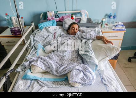 Gaza, Palestine. 13th août 2022. Rahaf Salman, une palestinienne blessée de 11 ans, se couche sur un lit d'hôpital après avoir perdu ses deux jambes et sa main droite lors d'une attaque aérienne israélienne sur Gaza. Le 07 août, Israël et les militants palestiniens à Gaza ont confirmé un cessez-le-feu de médiation égyptienne qui est entré en vigueur après trois jours d'échange d'attaques à la roquette et de frappes aériennes ayant entraîné la mort d'au moins 44 Palestiniens et 360 blessés, selon le Ministère palestinien de la santé. Crédit : SOPA Images Limited/Alamy Live News Banque D'Images