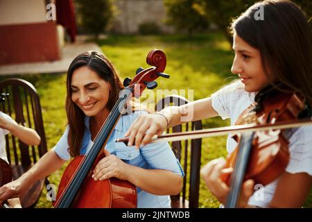 Jouer de la musique avec sa fille apporte sa joie. Une belle mère jouant des instruments avec son adorable fille à l'extérieur. Banque D'Images