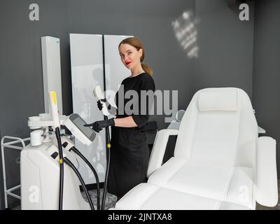 Le médecin-cosmétologue règle l'appareil pour le photoréjuvenation à l'aide de l'écran tactile. Banque D'Images