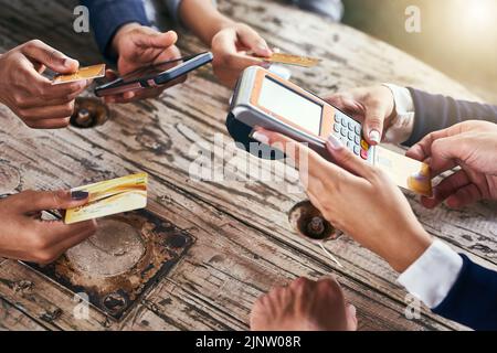 Qui paient en premier. Photo en grand angle d'un groupe d'hommes d'affaires qui paient leurs factures avec des cartes de crédit tout en étant assis autour d'une table à l'extérieur pendant Banque D'Images