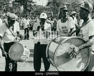 Photographie en noir et blanc d'un groupe de Bajan jouant de la musique populaire traditionnelle lors d'un défilé à la Barbade, avec une grande foule en arrière-plan Banque D'Images