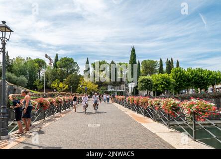 Touristes sur le pont dans la ville de Peschiera del Garda, lac de Garde, province de Vérone, Vénétie région du nord de l'Italie. Charmante citadelle fortifiée Banque D'Images
