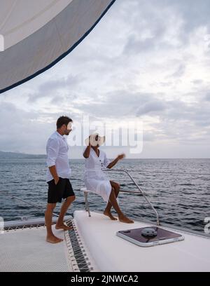 Un couple d'hommes et de femmes regardant le coucher du soleil depuis un bateau à voile dans la mer des Caraïbes Sainte-Lucie ou Sainte-Lucie. Hommes et femmes sur une excursion en bateau avec un bateau à voile Banque D'Images