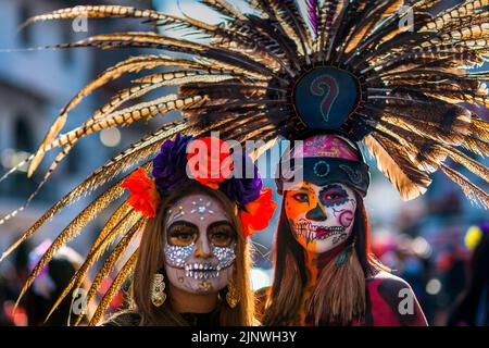 Une fille mexicaine, habillée comme la Catrina et portant une coiffe en plumes Aztec, participe aux célébrations du jour des morts à Taxco, au Mexique. Banque D'Images