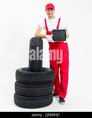 Mécanicien de voiture amical avec pneus et clé Banque D'Images