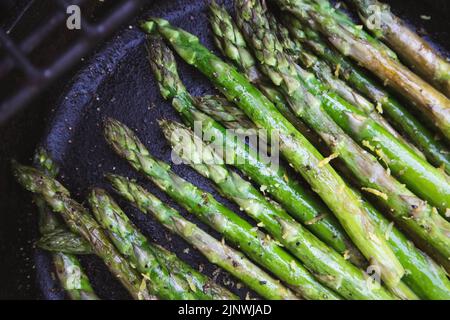 Asperges avec zeste de citron grillées à l'extérieur dans une poêle en fonte Banque D'Images