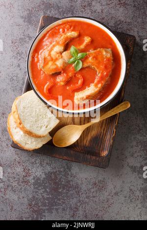 Soupe de tomate avec carpe de poisson de rivière, légumes et paprika en gros plan dans un bol sur la table. Vue verticale du dessus Banque D'Images