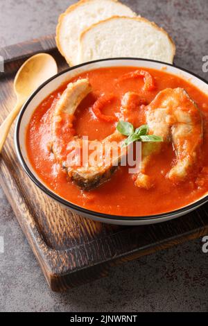 Soupe de tomate avec carpe de poisson de rivière, légumes et paprika en gros plan dans un bol sur la table. Verticale Banque D'Images