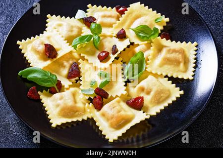 raviolis italiens avec remplissage de chorizo ricotta servi sur une assiette noire avec chorizo frit, gros plan Banque D'Images