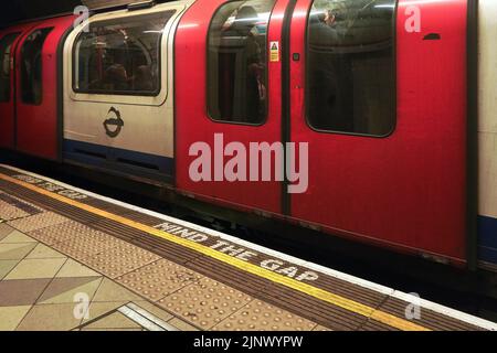 Londres, Royaume-Uni - 01 février 2019: ATTENTION AU TEXTE DE L'ÉCART au sol de la station de métro de Londres, en train d'attente derrière la ligne blanche et jaune Banque D'Images