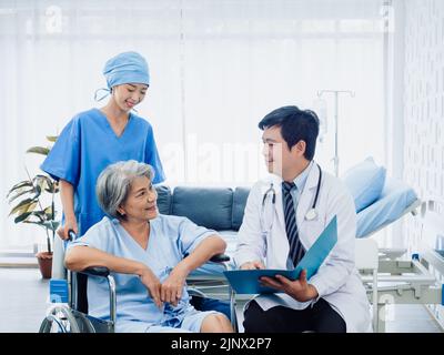 Heureuse femme âgée patients en fauteuil roulant souriant avec des médecins chirurgiens masculins et des assistants infirmiers professionnels féminins dans la salle blanche de récupération à hos Banque D'Images