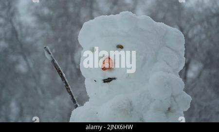 Joyeux bonhomme de neige drôle, sur fond d'une forte chute de neige. Banque D'Images