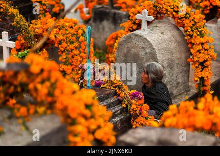 Une femme indigène Mixtec est assise parmi les tombes fleuries dans un cimetière lors des célébrations du jour des morts à Metlatónoc, au Mexique. Banque D'Images
