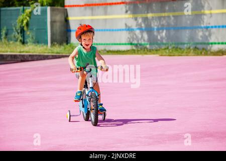 Un petit vélo pour garçon avec des roues d'apprentissage sur une surface colorée Banque D'Images