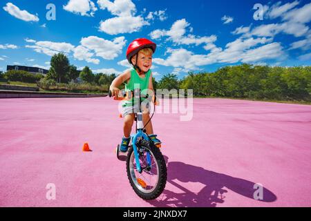 Les enfants s'y promenez à vélo avec des roues d'apprentissage autour des cônes Banque D'Images