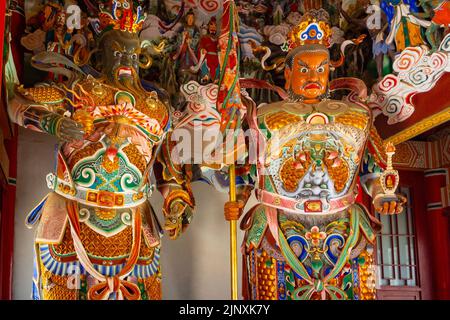 Deux statues religieuses traditionnelles chinoises à l'intérieur d'un temple. Les sculptures ou les symboles ont des vêtements multicolores. Banque D'Images