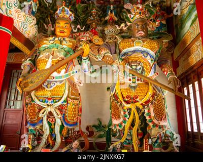 Deux statues religieuses traditionnelles chinoises à l'intérieur d'un temple. Les sculptures ont des vêtements multicolores. Banque D'Images
