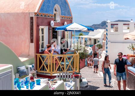 Un couple s'assoit avec des boissons sur la petite terrasse d'Un café dans la ville d'Oia, Santorini, les îles grecques, la Grèce. Banque D'Images
