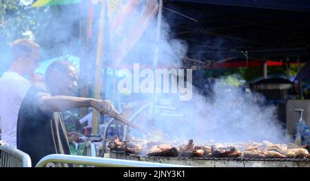 Manchester, Royaume-Uni, 14th août 2022. Un homme cuit le poulet dans une cabine vendant de la nourriture. Le Manchester Caribbean Carnival revient à Alexandra Park, Manchester, Angleterre, Royaume-Uni, après une absence de deux ans due à Covid 19. Le thème du Carnaval est «unité», il célèbre 50 ans d’histoire des Caraïbes et de l’Afrique à Manchester et il marque soixante ans d’indépendance jamaïcaine. Les organisateurs disent : « le Manchester Caribbean Carnival est un festival annuel qui apporte la saveur et la fête des Caraïbes pour un week-end à Manchester à travers les sons de Reggae, Calypso et Soca. » Crédit : Terry Waller/Alay Live News Banque D'Images