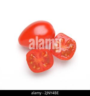 Deux petites tomates prune sur blanc, une entière et une coupée en deux Banque D'Images