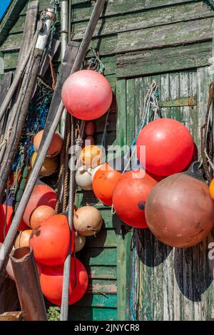 des flotteurs de pêche colorés accrochés sur le côté d'un vieux temps passé de mauvais temps battus ont traversé la cabane de pêcheurs sur la côte à hastings dans le kent, au royaume-uni, flottent. Banque D'Images