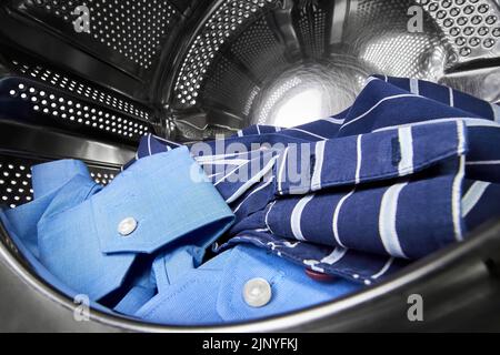 Gros plan d'une porte ouverte dans le lave-linge avec des chemises sales à l'intérieur Banque D'Images