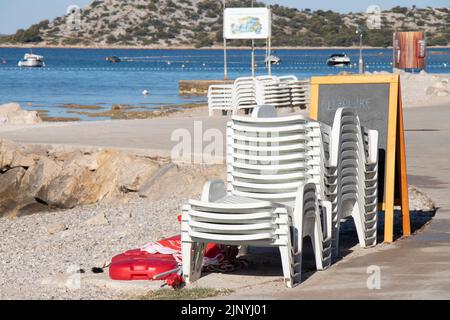 Vodice, Croatie - 13 juillet 2022: Chaises longues en plastique et parasols sur une plage vide en Croatie Banque D'Images