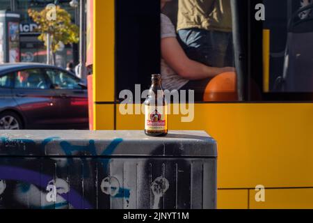 Une bouteille vide abandonnée de bière de marque Schultheiss locale dans son habitat naturel dans les rues animées de Berlin, en Allemagne. Banque D'Images