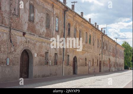 Des fenêtres bordent le mur extérieur d'un bâtiment de la citadelle en brique et plâtre à Osijek, en Croatie. Le long bâtiment est en état de réparation. Banque D'Images