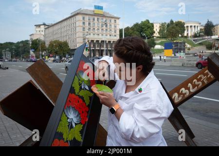 Un artiste peint des barricades anti-tank de hérisson dans le centre de Kiev. Banque D'Images