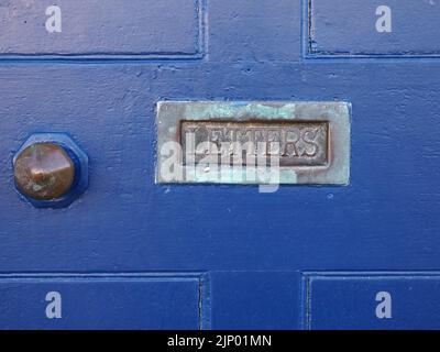 Boîte aux lettres antique avec verdigris oxydé et lettres dans ancienne porte en bois peint en bleu à côté de poignée de porte en laiton Banque D'Images