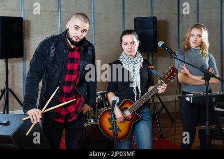 Trois bandmates se posant ensemble avec des instruments de musique dans la salle de répétition Banque D'Images