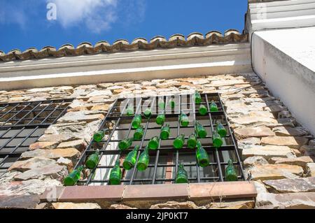 Maison de résidence rurale fenêtre décorée avec des bouteilles de verre vertes suspendues. Vue à angle bas Banque D'Images