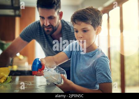 Prenez ces germes. Un père et un fils nettoyant le comptoir de cuisine ensemble à la maison. Banque D'Images