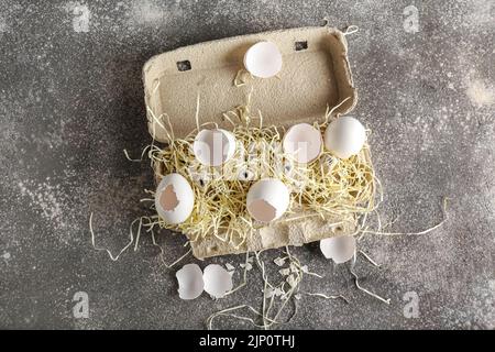 Support en carton avec coquilles d'œufs cassées sur fond sombre Banque D'Images